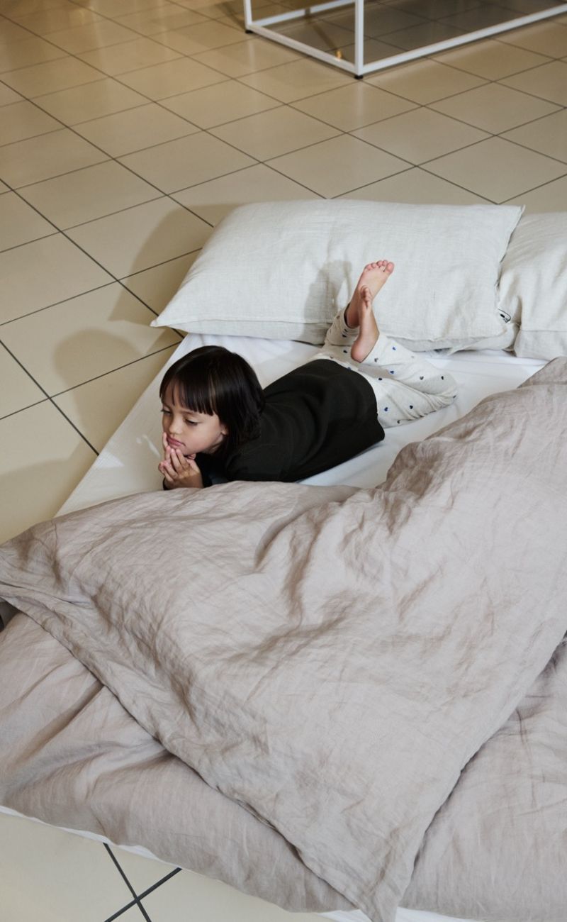 Flicka liggande på en vit madrass på golvet